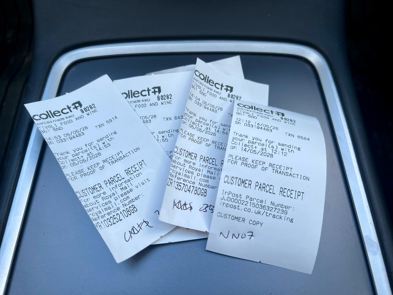 Handwritten notes on InPost and Royal Mail receipts in a car centre console